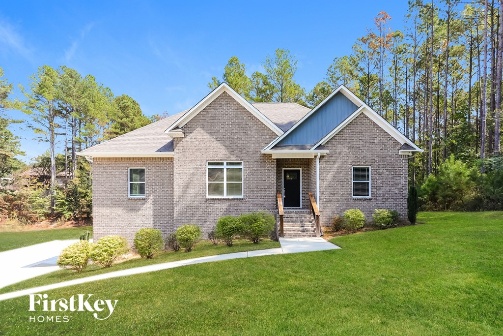A brick house with a porch and a front yard.