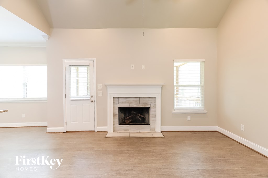 A large empty room with a fireplace and two windows.
