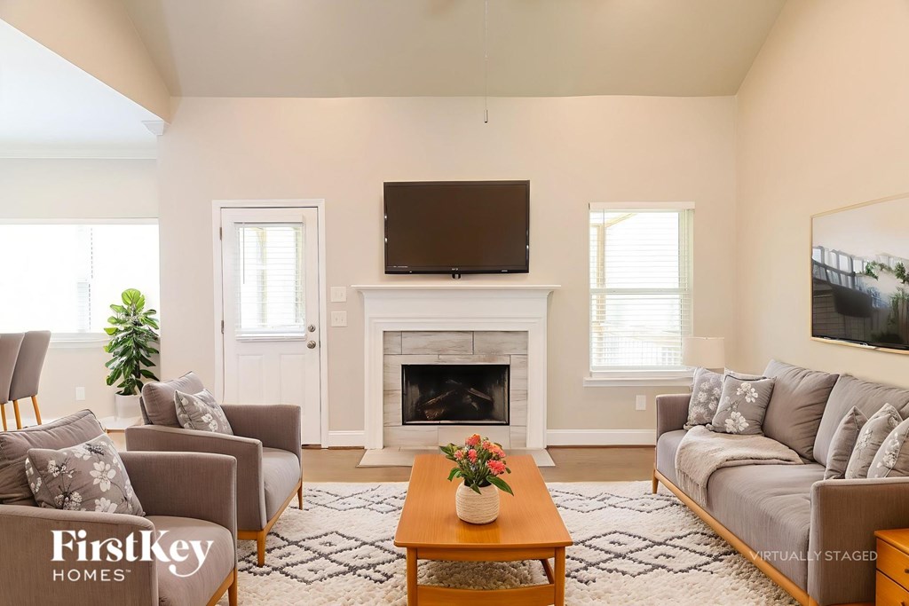 A living room with a fireplace and a flat screen TV mounted on the wall.
