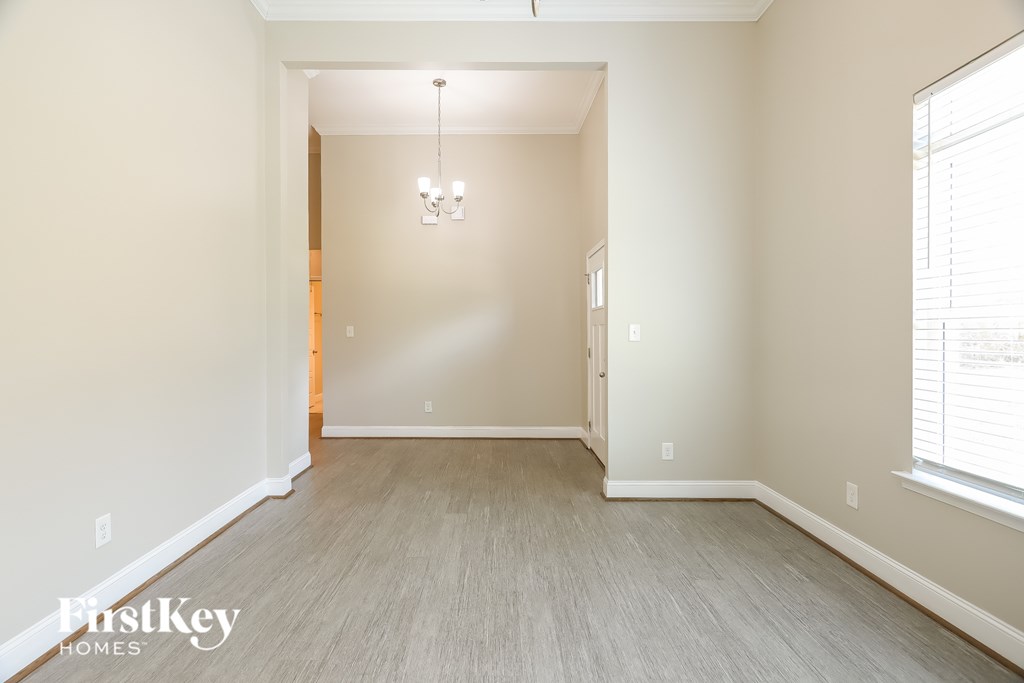 A room with a chandelier and a window with blinds.