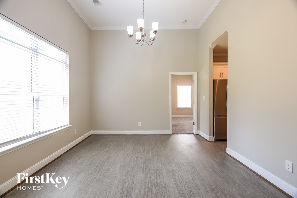 A spacious room with a chandelier and a doorway leading to another room.
