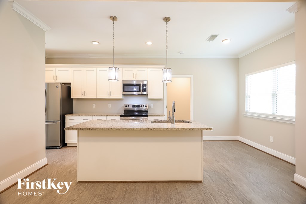 A kitchen with a refrigerator, microwave, oven, and sink.