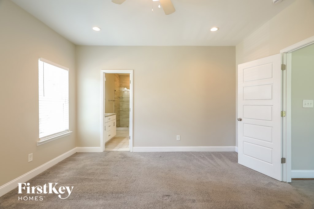 A room with a carpet floor and a ceiling fan.