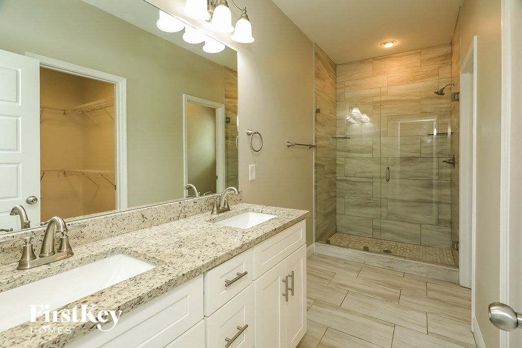 A bathroom with a marble countertop and a walk-in shower.