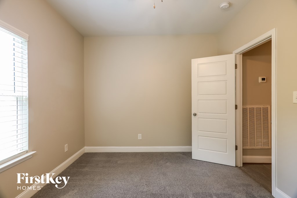 A room with a white door and a window with blinds.