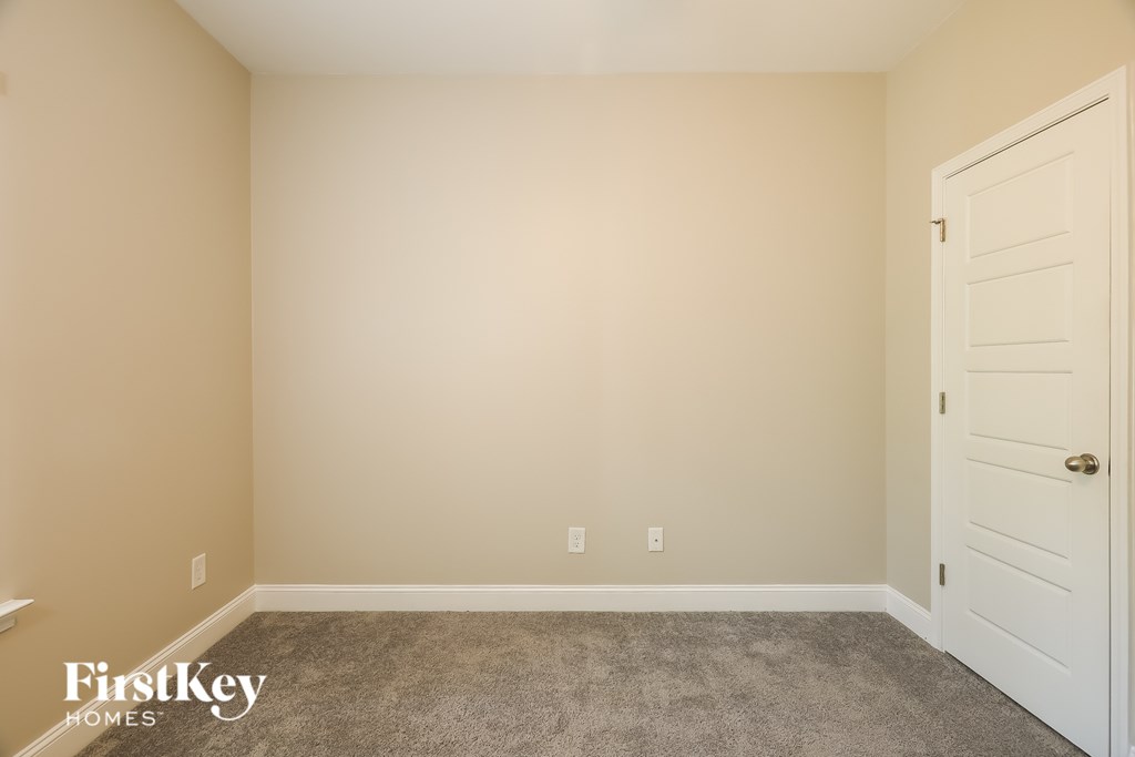 A room with a white door and carpeted floor.