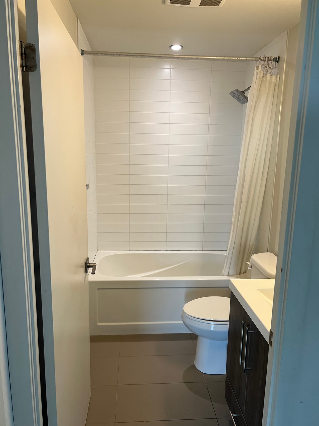 A white toilet sits in a bathroom next to a bathtub.