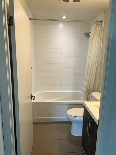 A white toilet sits in a bathroom next to a bathtub.