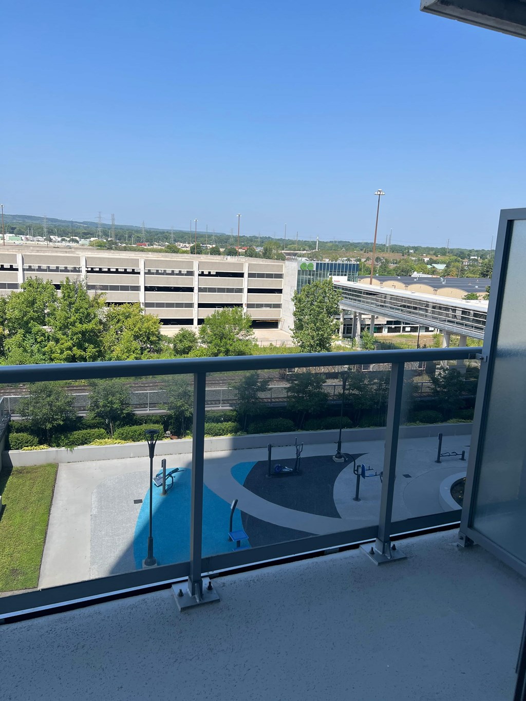 A view from a balcony overlooking a pool and a parking lot.