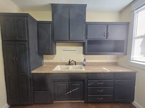 A kitchen with black cabinets and a granite countertop.