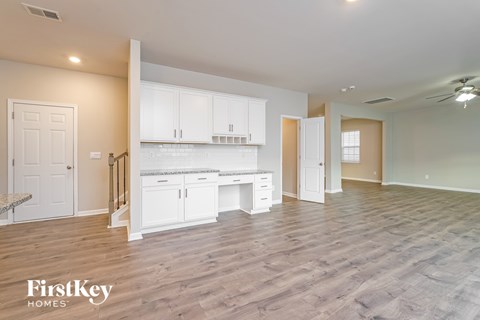 A spacious kitchen with white cabinets and a wooden floor.