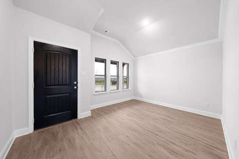 A room with a black door and wooden flooring.