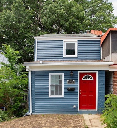 A blue house with a red door and mailbox.