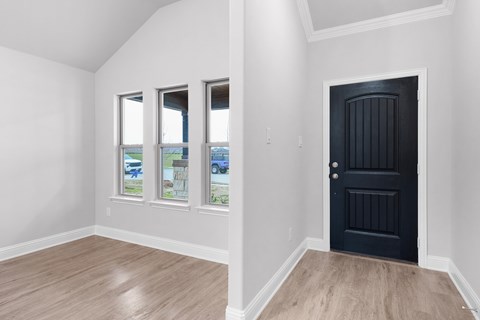 A room with a black door and three windows.