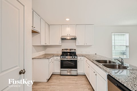 A kitchen with white cabinets and a granite countertop.