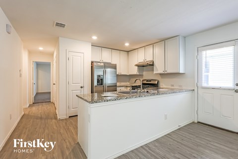 A kitchen with white cabinets and a granite countertop.