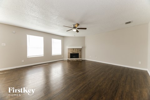 A spacious room with a fireplace and a ceiling fan.