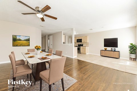 A dining room with a table set for six and a painting on the wall.