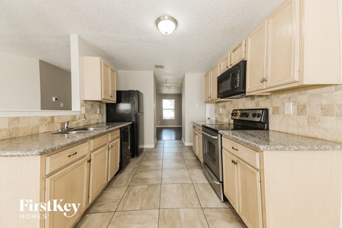 A kitchen with beige cabinets and a tiled floor.