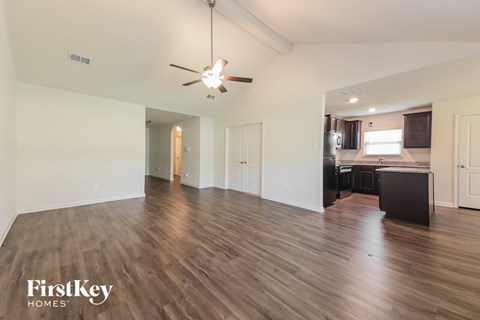 A spacious room with wooden flooring and a ceiling fan.