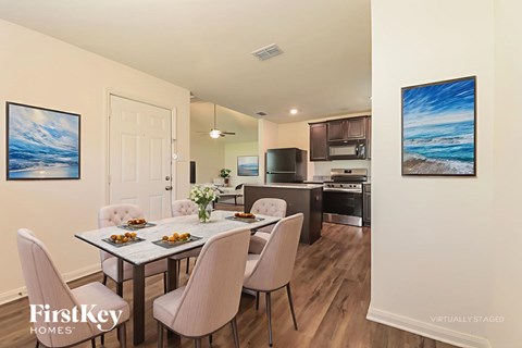 A dining room with a table set for two and a kitchen in the background.