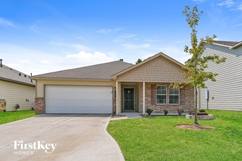 A house with a garage door and a tree in front.