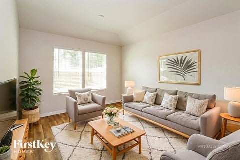 A living room with a grey couch, a wooden coffee table, and a painting on the wall.