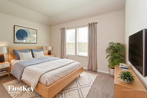 A bedroom with a large bed, a television, and a rug.