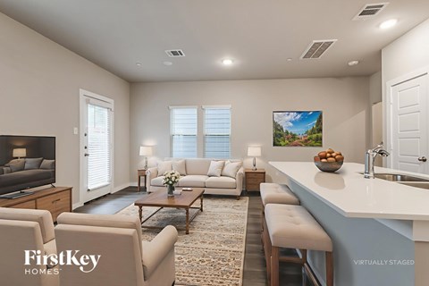 A modern living room with a large couch, a coffee table, and a flat-screen TV.