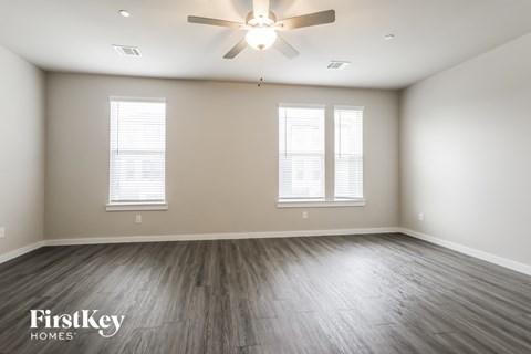 A spacious room with a ceiling fan and wooden flooring.