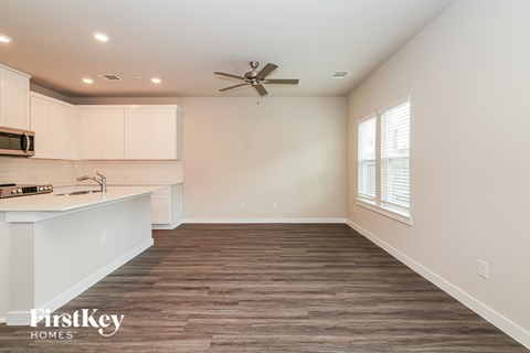 A spacious kitchen with white cabinets and a wooden floor.