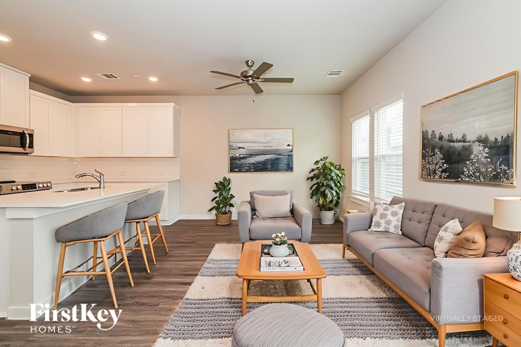 A well-lit, modern living room with a kitchen area in the background.