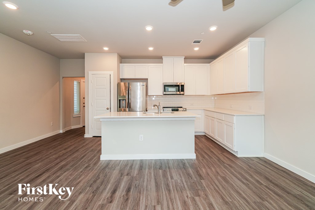 A kitchen with white cabinets and a wooden floor.