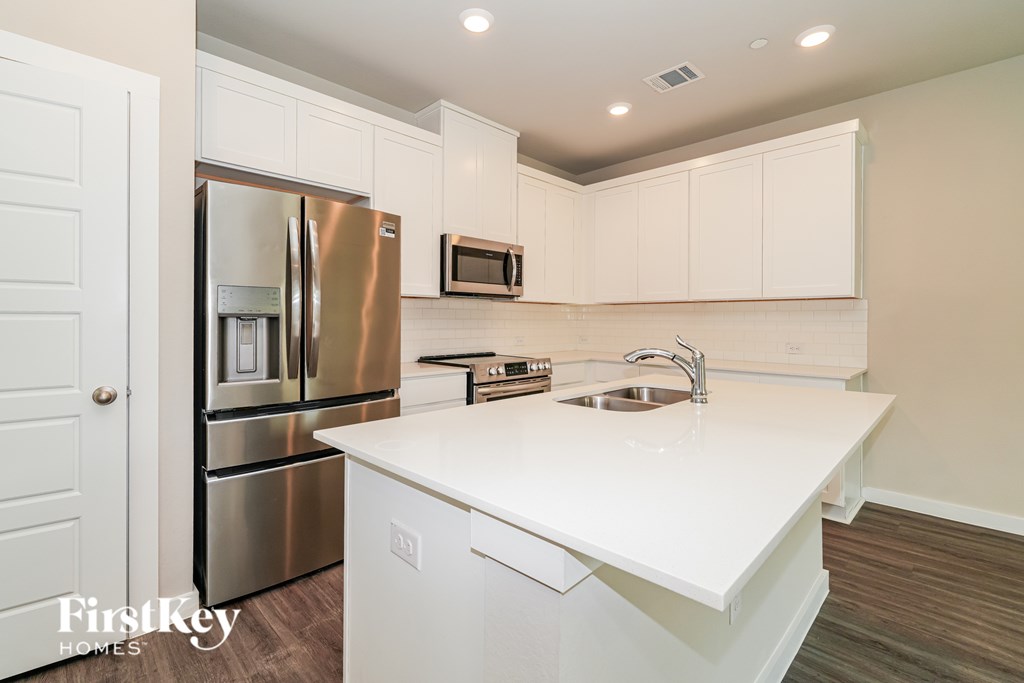 A kitchen with white cabinets and a stainless steel refrigerator.
