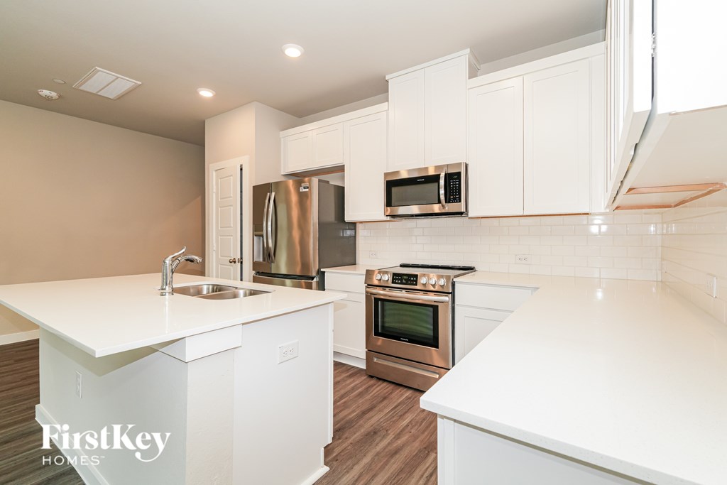 A modern kitchen with white countertops and stainless steel appliances.