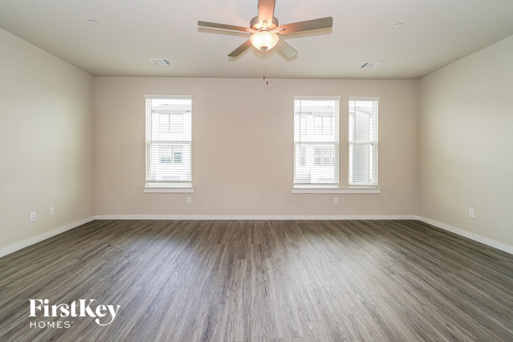 A room with a ceiling fan and two windows.