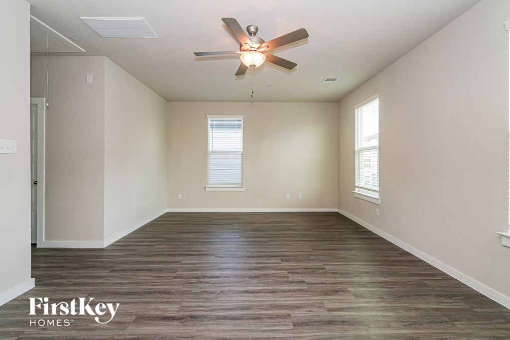 A spacious room with a ceiling fan and wooden flooring.