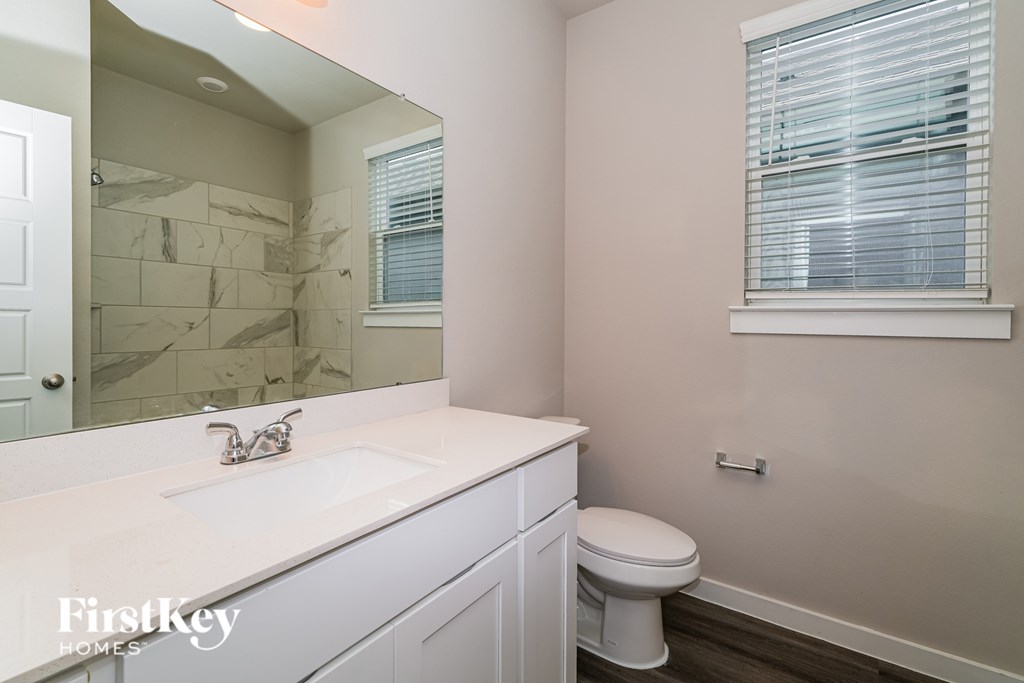 A white bathroom with a marble wall and a toilet.