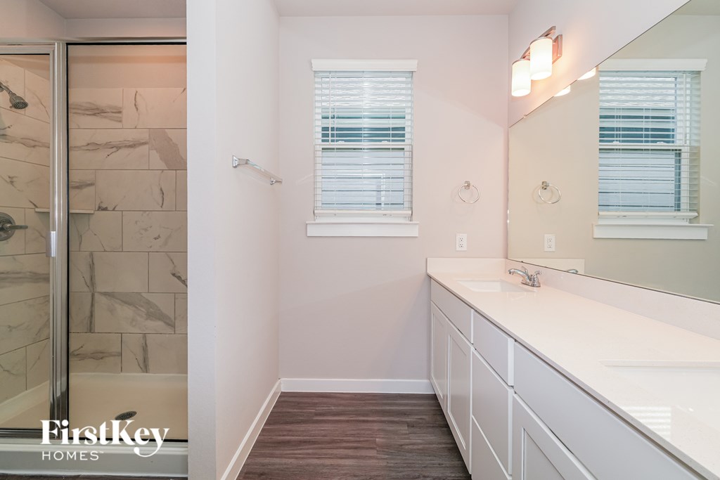 A bathroom with a marble tile shower and a white sink vanity.