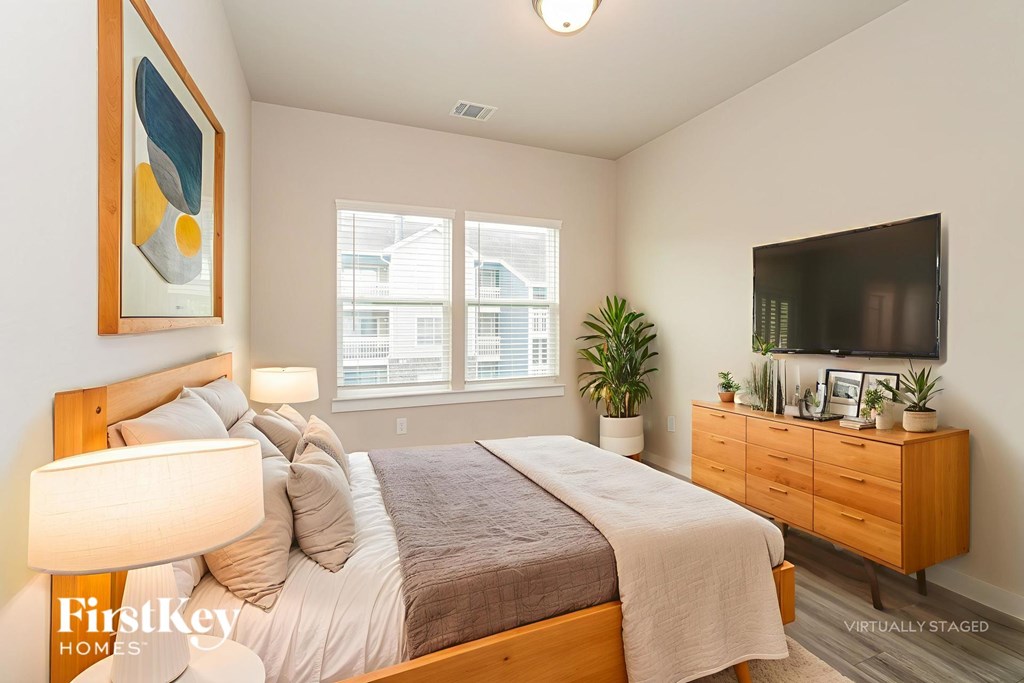 A bedroom with a bed, nightstand, and a painting on the wall.