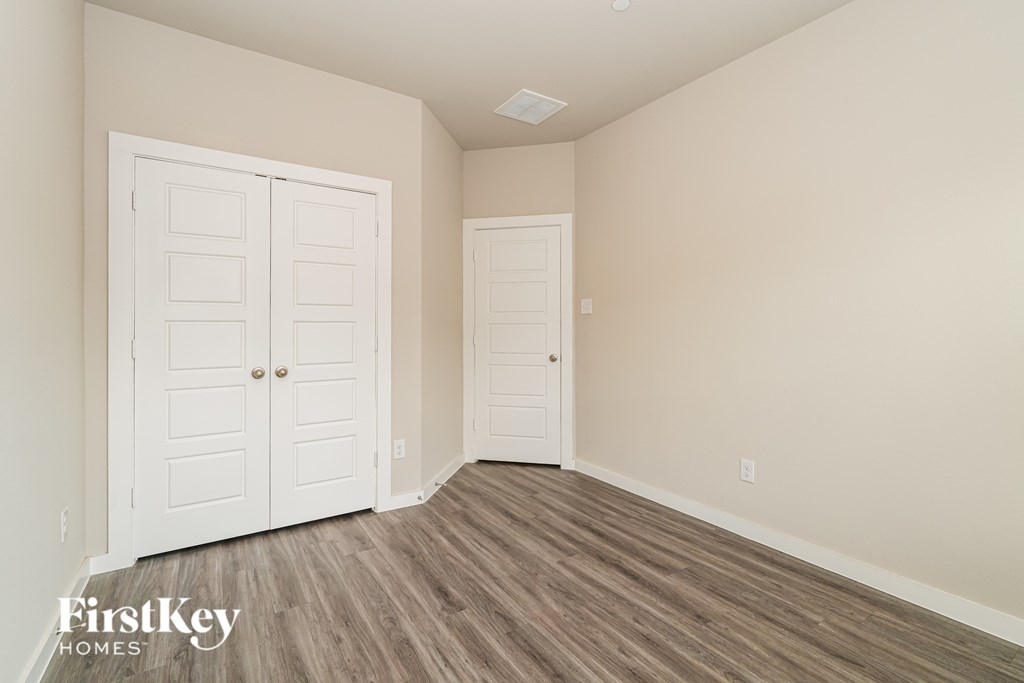 A room with a white door and a wooden floor.