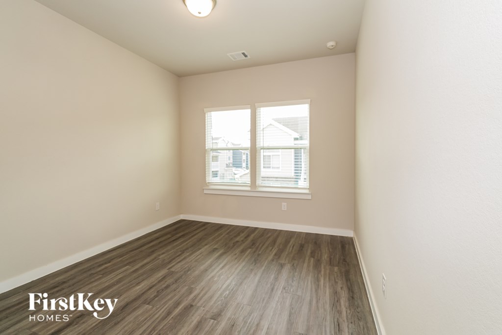 A room with wooden flooring and a window with blinds.