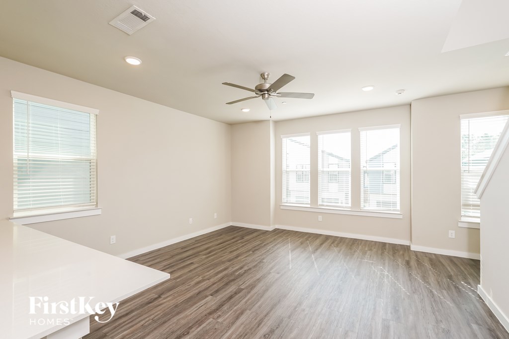 A spacious room with a ceiling fan and wooden flooring.
