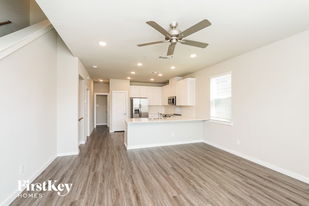 A spacious room with a ceiling fan and wooden flooring.