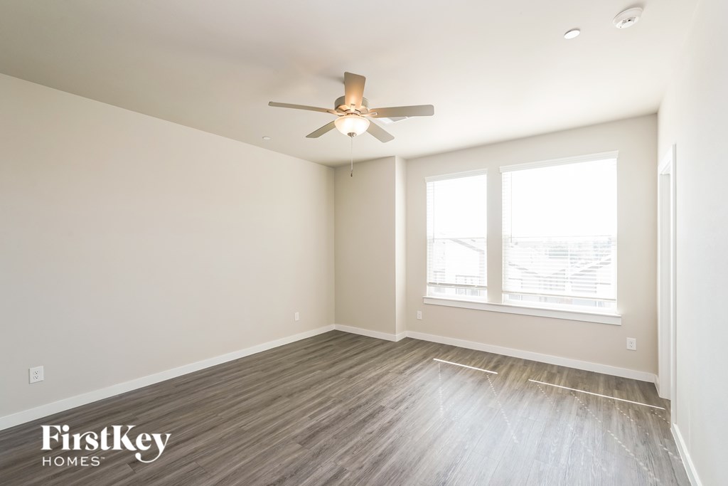 A room with a ceiling fan and wooden flooring.