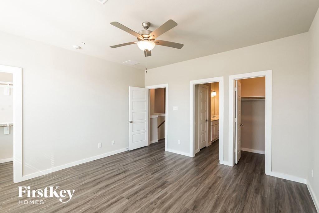 A room with a ceiling fan and wooden floors.