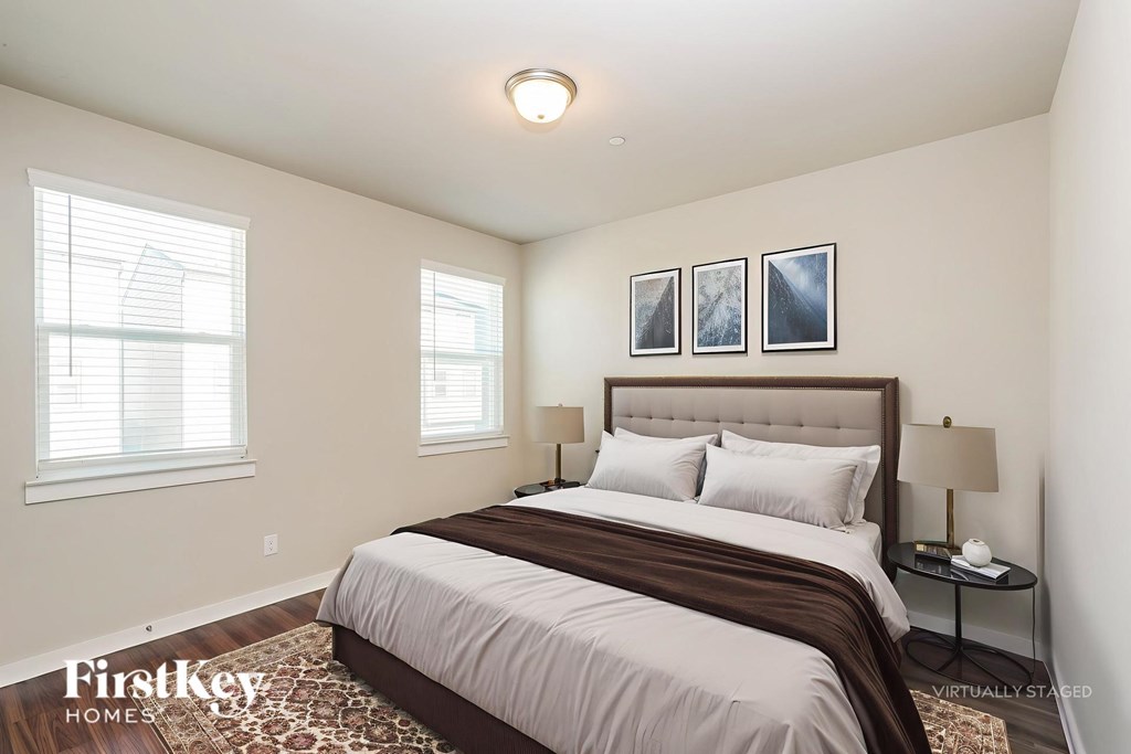 A bedroom with a large bed and two windows.