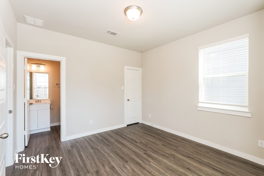 A room with a wooden floor and a window with blinds.