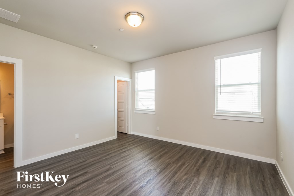 A spacious room with wooden flooring and a window on the right side.