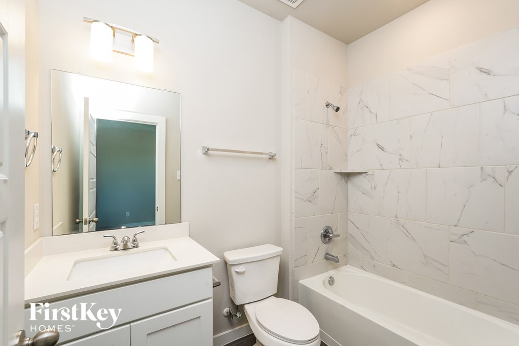 A white bathroom with a marble wall and a white toilet.